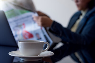 Business woman in suit, sitting and reading newspaper at office. 