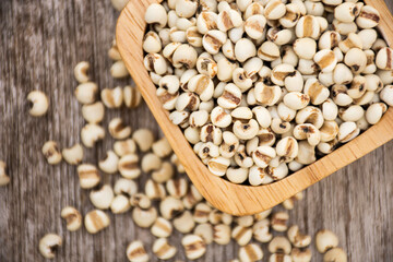 Adlay millet or job's tears in a wooden bowl on wood table background. Top view.