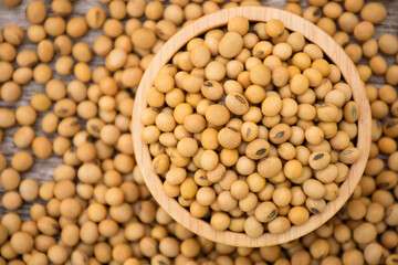 Closeup soy beans in wooden bowl isolated on wood table background. Overhead view. Flat lay.