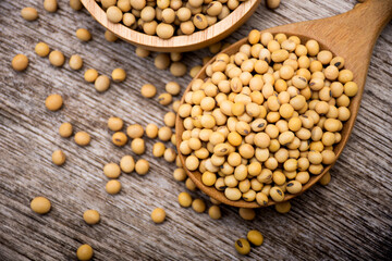 Closeup soy beans in wooden spoon isolated on wood table background. Overhead view. Flat lay.
