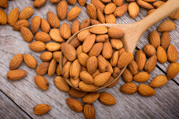 Almond nut in wooden spoon isolated on rustic wood table background. Top view. Flat lay. 