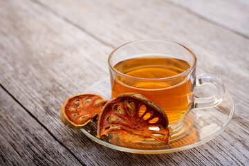 Bael fruit juice or quince tea and dried bael sliced fruit (Aegle marmelos or wood golden apple) isolated on old rustic wood table background. Healthy drinks concept. Vintage tone .