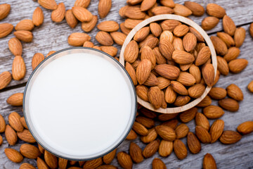 Closeup at glass of Almond milk with almond seeds isolated on wood table background. Healthy drinks concept. Top view. Flat lay.