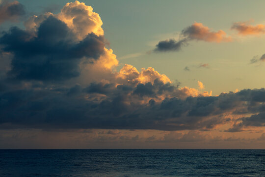 Shocking sun drop with vibrant colors. Golden clouds at sunset. Vacation landscape in the tropics.