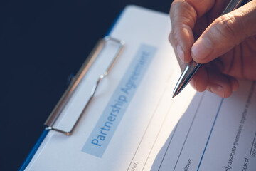 Close up of business man hand with a pen signing partnership contract form
