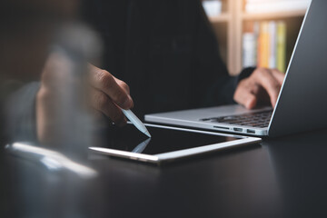 Man working on digital tablet and laptop computer at home office or student learning online