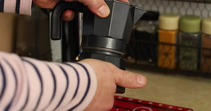 Someone picks up a stovetop espresso maker, unscrews and separates all the parts then adds water to bottom part.