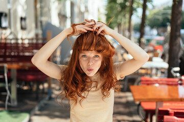 Young woman making bangs with her long red hair