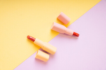 Red lipsticks on yellow and purple background. Top view. Flat lay.