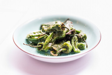 A plate of green peppers on a white background