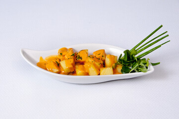 A plate of potatoes with sauce on a white background