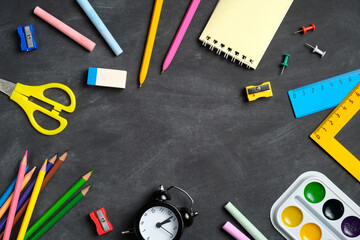 Fototapeta na wymiar Frame of colorful school supplies on blackboard background. Back to school concept. Flat lay, top view, overhead.
