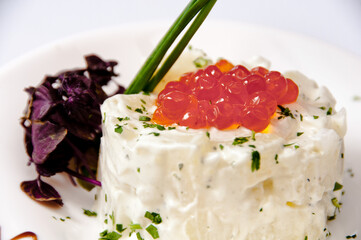 A plate of potato salad with caviar on a white background