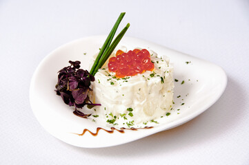 A plate of potato salad with caviar on a white background