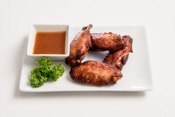 A plate of fried chicken with sauce on a white background