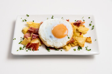 A plate of potatoes with egg and ham on a white background