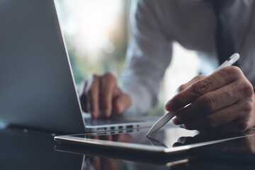 Businessman working on digital tablet and laptop computer in modern office