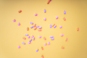 Top view - Pastel colourful vitamin medicine over bright yellow background. Messy and seperate.
