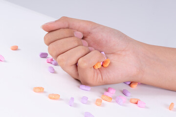 Hand of patient grabbing medicine pills over white background.