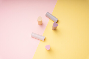 Flat lay fashion set - Brown pink lipstick and brush for powder on pastel background.