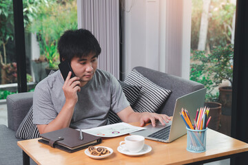 A man in casual wear using phone and working at home office.