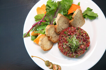 Raw tartar meat with spices, croutons and herbs. Beef tartar with capers. Beef tartar with slices of bread.  Raw meat tartare for gourmet meat.