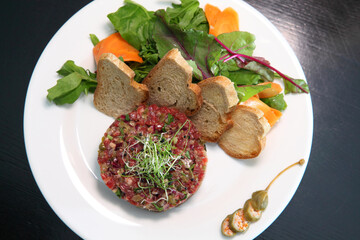 Raw tartar meat with spices, croutons and herbs. Beef tartar with capers. Beef tartar with slices of bread.  Raw meat tartare for gourmet meat.