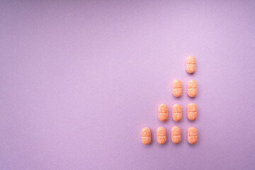 Top view - Orange pills over purple pink background. Triangle shape.