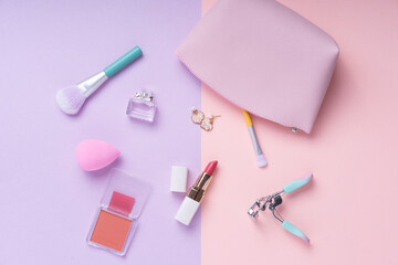 Top view - Cosmetic make up collection set over purple and pink background.