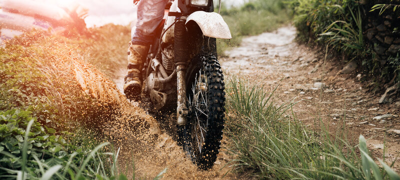 rider on a motorcycle rides a puddle of mud  splashing around