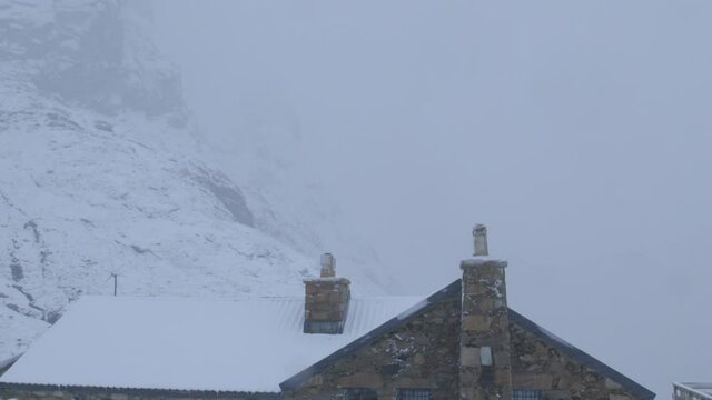 Cropped static shot of Ben Nevis CIC hut during cloudy winters day with snow covered mountainside in the background.