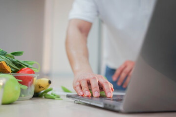 close up young man using laptop to searching content about cooking recipe of vegan food from...