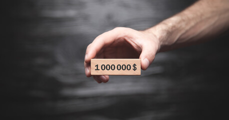 Male hand showing 1.000.000$ on wooden block.