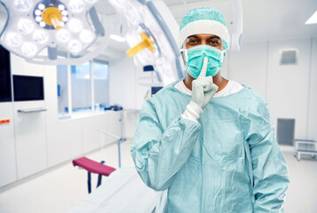 Fototapeta na wymiar medicine, surgery and people concept - indian male doctor or surgeon in mask and protective wear over operating room at hospital background