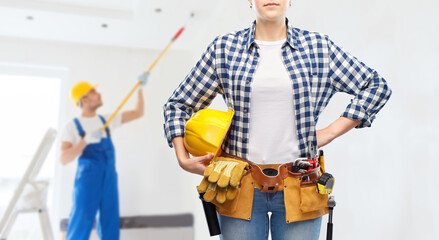 Fototapeta na wymiar repair, construction and building concept - woman or builder with helmet and working tools on belt over painter painting ceiling background