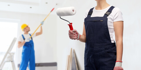 repair, construction and building concept - close up of female painter or builder with paint roller...