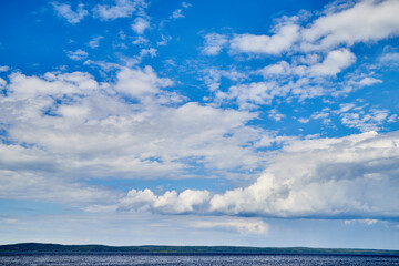 Beautiful landscape with blue sky, white clouds, water of lake and the road that goes to the horizon.