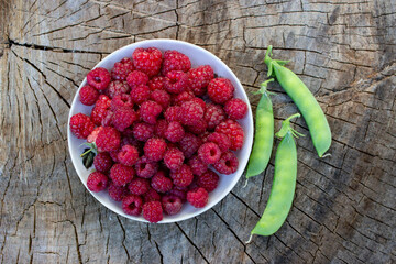 Raspberries, ripe, delicious pink. A full plate of white porcelain. There are scattered berries and...