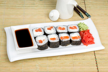 Sushi on a white plate with sauce and seasonings