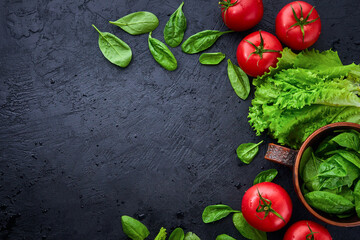 Fresh grape tomatoes with salad and spinach Leaves on black stone background. Vegan veggies diet food. Herb, red tomatoes, cooking concept.