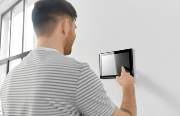 automation, internet of things and technology concept - man looking at tablet pc computer at smart home