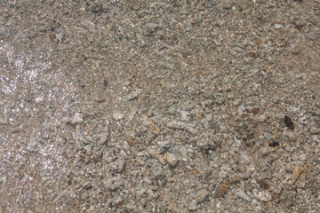 natural filled frame close up background wallpaper of a wet brown beige gravel beach rocks and stones surface