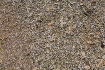 natural filled frame close up background wallpaper of a wet brown beige gravel beach rocks and stones surface