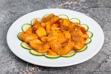 Pike perch in batter on a white plate, decorated with cucumbers