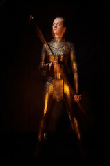 Valkyrie girl in shiny military armor and with a spear in a dark room with plants and vines. Model...