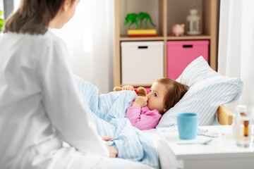 healthcare, medicine and people concept - doctor and sick little girl lying in bed at home