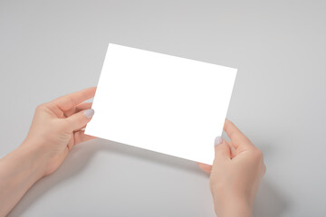 Woman's holding a blank piece of paper over a gray background