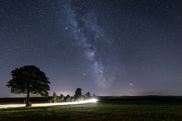 Milchstraße in der Nacht und Leuchtspuren von einem Auto © ohenze