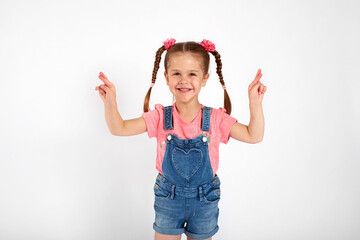 Little girl crossed her fingers, shut her eyes and makes a wish, isolated on white background