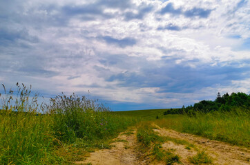 road in a field against a stormy sky